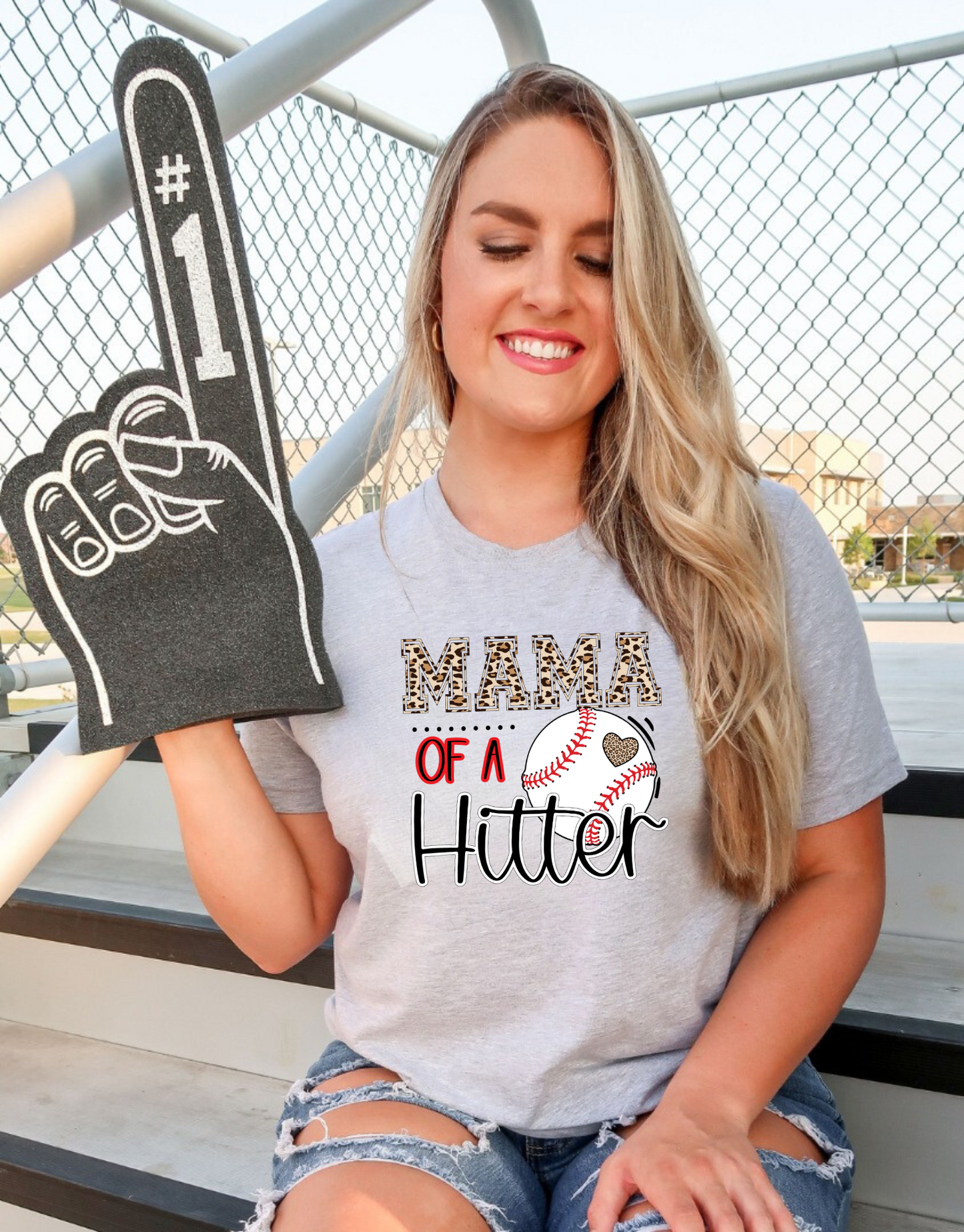 Baseball Mom Shirt with the phrase 'Mom of a Hitter' in trendy leopard print. A cute and stylish graphic tee for baseball game days and proud baseball moms. Perfect for showcasing team spirit and fashionable support.