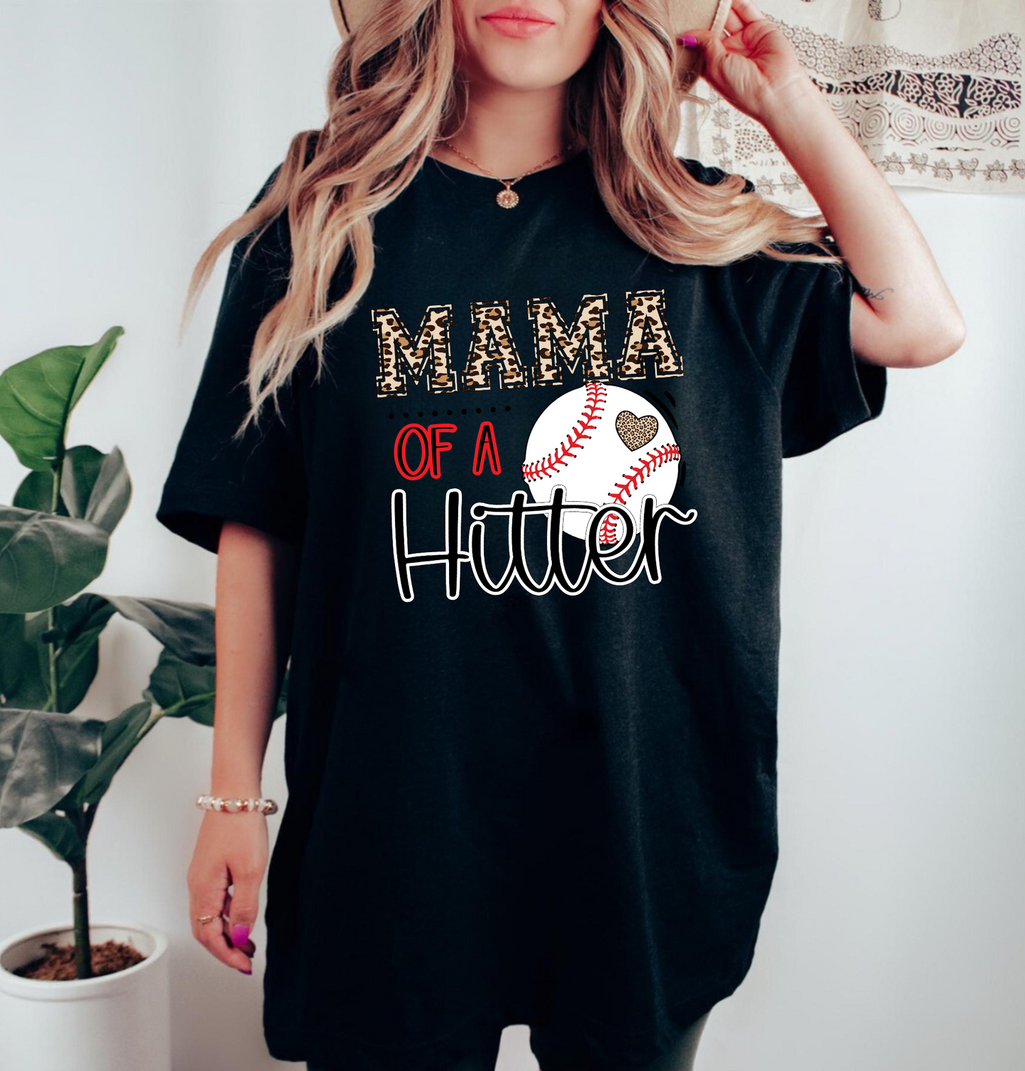 Baseball Mom Shirt with the phrase 'Mom of a Hitter' in trendy leopard print. A cute and stylish graphic tee for baseball game days and proud baseball moms. Perfect for showcasing team spirit and fashionable support.