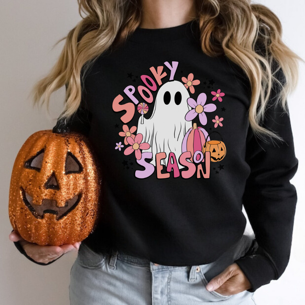A trendy and oversized Halloween sweatshirt in pink, featuring a cute ghost design with the text 'Spooky Season'. This pastel pink fall sweatshirt adds a playful touch to your autumn wardrobe.